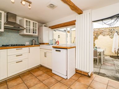 A kitchen with white cabinets wooden countertops dishwasher and a patio with outdoor dining furniture at The Yellow House 13 King Street in Dawlish