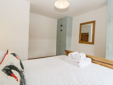 A bedroom with a bed and folded towels on it a mirror on the wall and a cupboard in the corner at The Yellow House 13 King Street in Dawlish