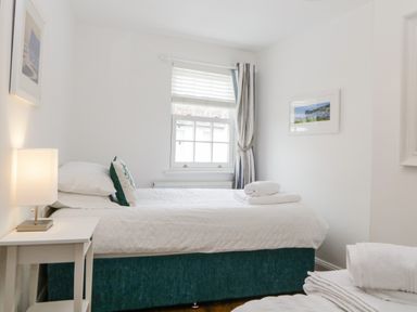 A bedroom with a single bed bedside table with lamp and window with striped curtains at The Yellow House 13 King Street in Dawlish