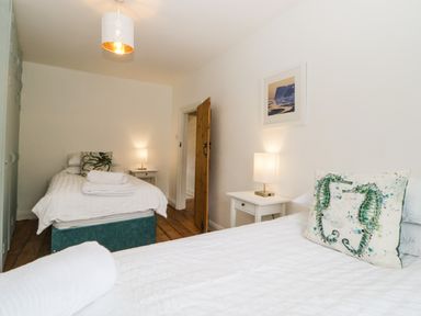 A bedroom with two single beds white bedside tables lamps and a wooden door at The Yellow House 13 King Street in Dawlish