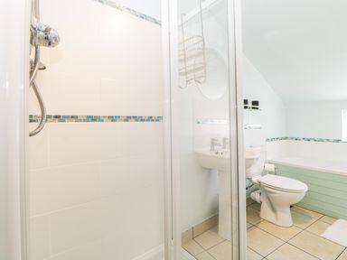 A bathroom with a shower, sink, toilet, bathtub, and tiled floor at The Yellow House 13 King Street in Dawlish