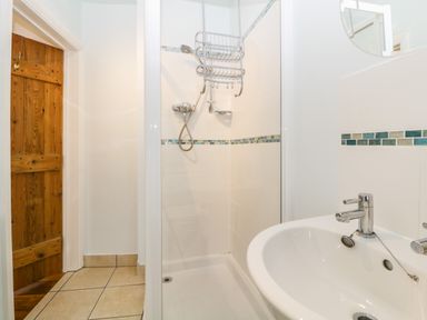 A bathroom with a shower area and a sink with a mirror above at The Yellow House 13 King Street in Dawlish