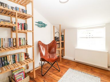 A reading room with wooden bookshelves a leather chair and a window at The Yellow House 13 King Street Dawlish