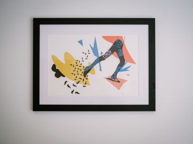 A framed abstract artwork of a person walking with blue patterned legs and colored shapes on a white wall at Craig Cottage in Bowness-On-Windermere