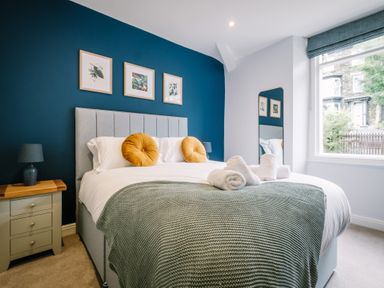 A bedroom with a bed, bedside tables, lamps and framed pictures on a wall at Craig Cottage in Bowness-On-Windermere