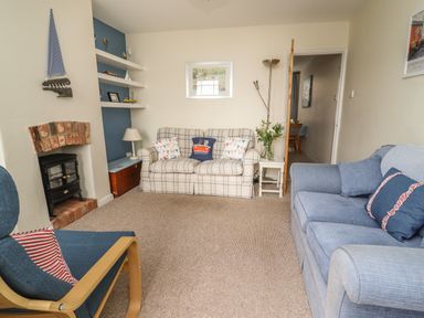 A living room with two sofas armchair fireplace and bookshelves at 9 Harefield Cottages in Lympstone