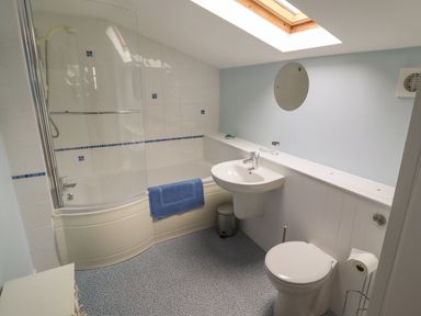 A bathroom with a bathtub shower mix toilet sink and skylight at 9 Harefield Cottages in Lympstone