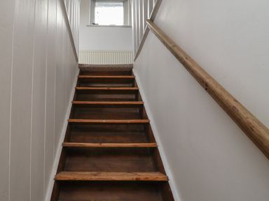 A wooden staircase with a handrail on the right and a window at the top at 9 Harefield Cottages in Lympstone