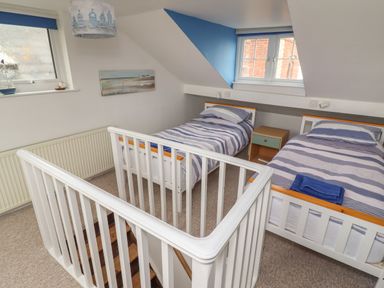 A bedroom with two single beds and a small bedside table near a window at 9 Harefield Cottages in Lympstone