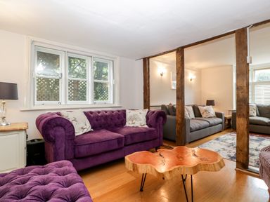 A living room with purple and grey sofas wooden beams and a wooden coffee table at Oakapple Cottage in Swan Green near Lyndhurst