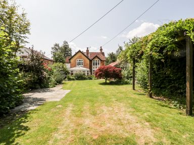 A garden with a lawn a pathway plants and a house in the background at Oakapple Cottage Swan Green near Lyndhurst