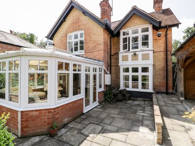 An exterior view of a brick house with white framed bay windows and a white conservatory at Oakapple Cottage in Swan Green near Lyndhurst