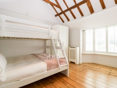 A bedroom with a white bunk bed a wardrobe a radiator cover and a large window with shutters at Oakapple Cottage in Swan Green near Lyndhurst