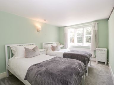 A bedroom with two single beds bedside tables and a window at Oakapple Cottage in Swan Green near Lyndhurst