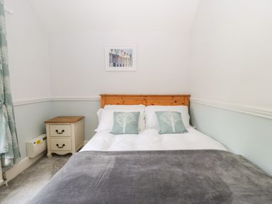 A bedroom with a wooden bed frame a bedside table and a framed picture above the bed at Oakapple Cottage in Swan Green near Lyndhurst