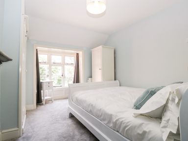 A bedroom with a white bed white wardrobe and a window with curtains at Oakapple Cottage in Swan Green near Lyndhurst