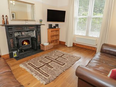 A living room with a fireplace television on a wooden shelf and two leather sofas at Ty Capel in Betws-Y-Coed