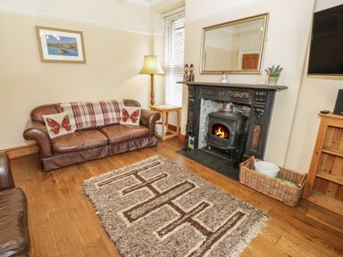 A living room with a leather sofa armchair rug fireplace and a wall mirror at Ty Capel in Betws-Y-Coed