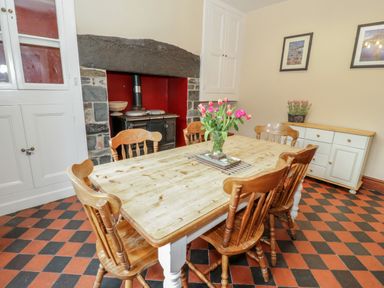 A dining room with wooden table and chairs a fireplace with stove and a cabinet against the wall at Ty Capel in Betws-Y-Coed