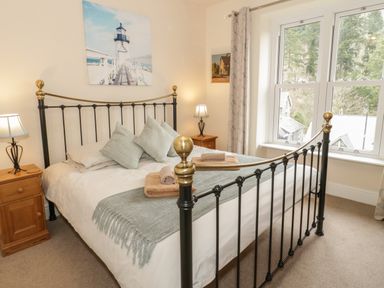 A bedroom with a black and gold metal bed frame pillows on the bed bedside tables with lamps and large window at Ty Capel in Betws-Y-Coed