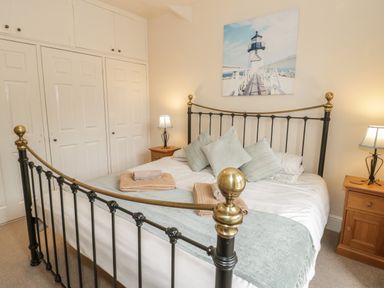 A bedroom with a double bed with metal frame pillows folded towels bedside tables lamps and built-in wardrobes at Ty Capel in Betws-Y-Coed