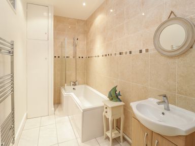 A bathroom with a bathtub shower sink small table and round mirror at Ty Capel in Betws-Y-Coed