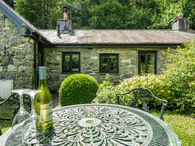 A table and chairs with wine and glasses at Tyn Y Ffynnon in Betws-Y-Coed