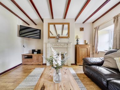 A living room with a television, fireplace, and wooden furniture at Tyn Y Ffynnon in Betws-Y-Coed