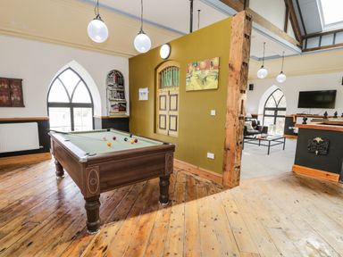 A room with a pool table wooden floor exposed beam and arched windows at Greystones Chapel in Cwm-y-Glo near Llanrug