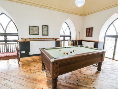 A game room with a pool table and wooden floors at Greystones Chapel in Cwm-y-Glo near Llanrug