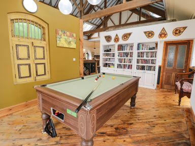 A room with a pool table wooden floor bookshelves and a wooden door at Greystones Chapel in Cwm-y-Glo near Llanrug