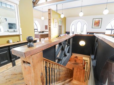 A staircase with wooden banisters leading down with a pool table and seating area in the background at Greystones Chapel in Cwm-y-Glo near Llanrug