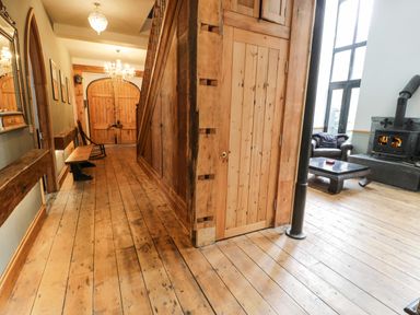 A hallway with wooden floors a bench and a rocking chair next to wooden double doors at Greystones Chapel in Cwm-y-Glo near Llanrug