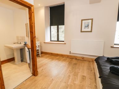 A bedroom with wooden floor and sinks in an adjoining room at Greystones Chapel in Cwm-y-Glo near Llanrug