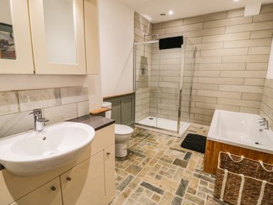 A bathroom with a sink, toilet, shower cabin, bathtub, and a basket at Greystones Chapel in Cwm-y-Glo near Llanrug