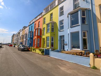 A street with colorful terraced houses and parked cars at Enfys in Criccieth