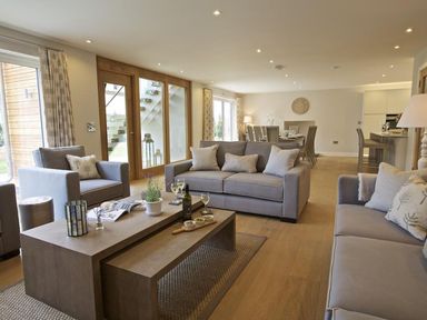 An open living and dining area with sofas armchairs coffee tables dining table and kitchen at 3 The Drive Hillfield Village Dartmouth
