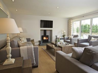 A living room with gray sofas a wood burning stove and a TV mounted on the wall at 3 The Drive Hillfield Village Dartmouth