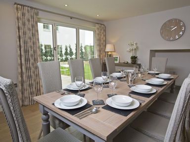 A dining room with a wooden table set for eight people with plates glasses and cutlery at 3 The Drive Hillfield Village in Dartmouth