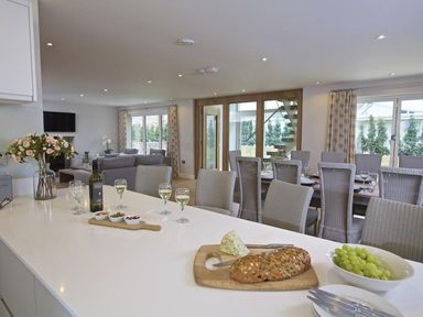 A kitchen island with bread grapes wine and snacks overlooking a dining area and living room at 3 The Drive Hillfield Village in Dartmouth