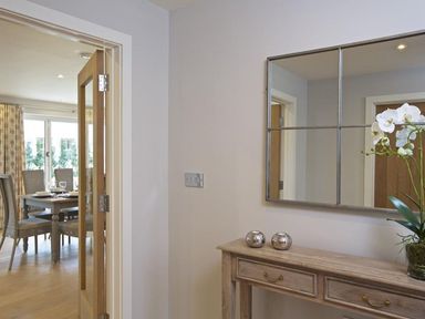 A hallway with a wooden console table and a large wall mirror overlooking a dining room with a table and chairs at 3 The Drive Hillfield Village in Dartmouth