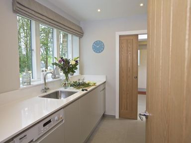 A kitchen with a sink countertop flowers on the counter and a clock on the wall at 3 The Drive Hillfield Village in Dartmouth