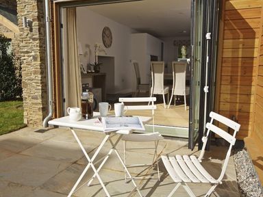 A patio with a white metal table and chairs with a coffee press and mugs outside a dining room at 3 The Drive Hillfield Village in Dartmouth