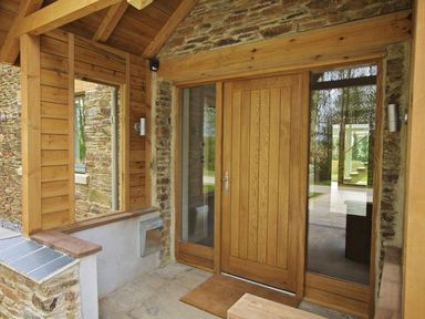 An entrance with a wooden door flanked by glass panels under a wooden roof at 3 The Drive Hillfield Village Dartmouth