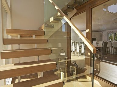 A wooden staircase with glass railing next to a dining area with chairs at 3 The Drive Hillfield Village in Dartmouth