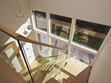 A staircase with wooden steps and glass railing next to large windows with a view outside at 3 The Drive Hillfield Village in Dartmouth