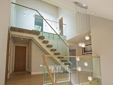 A stairway with glass railings and wood steps inside a modern house at 3 The Drive Hillfield Village Dartmouth