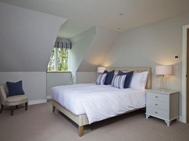 A bedroom with a bed with pillows beside a window and a nightstand with a lamp at 3 The Drive Hillfield Village in Dartmouth