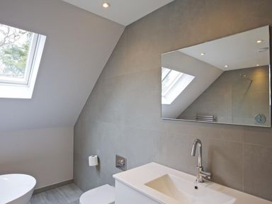 A bathroom with a sink and faucet a toilet a mirror and a skylight window at 3 The Drive Hillfield Village Dartmouth