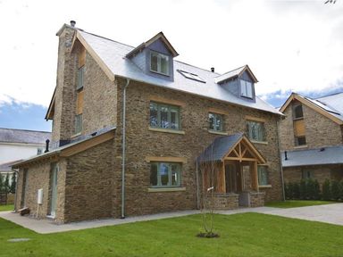 A stone house with a slate roof and dormer windows with a small lawn in front at 3 The Drive Hillfield Village Dartmouth